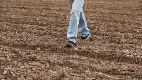 Agriculteur marchant sur des terres agricoles, planifiant une nouvelle saison de semis