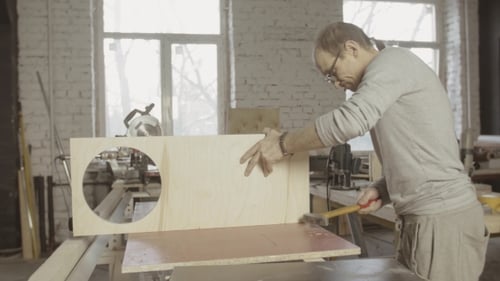 Man Hammering Wood in Bright Workshop