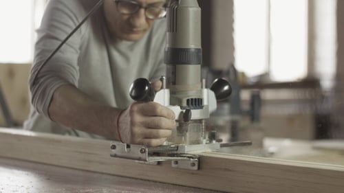 Adult Using Router Tool on Wood in Workshop