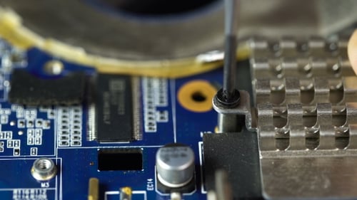 Technician Unscrewing Component on Computer Motherboard Close Up