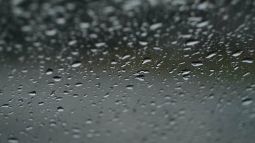 Raindrops Streaking Down Glass Window on Wet Day