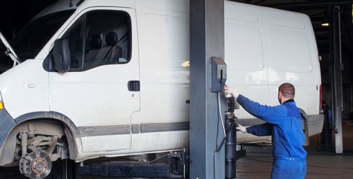 Mechanic Repairing Van in Garage on Lift