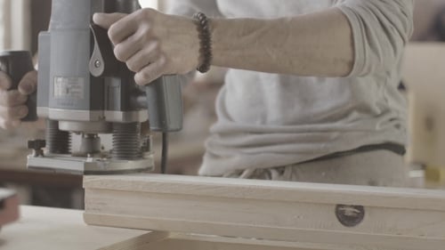 Man Using Router on Wood in Workshop