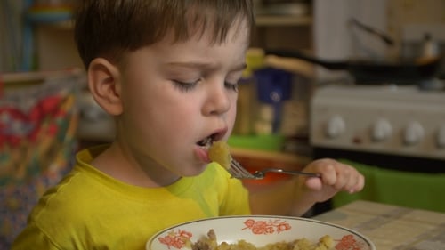 Boy Of Three Years In The Yellow Shirt Is Eating