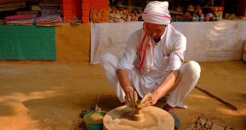 Potier professionnel qualifié lançant le volant du potier et façonnant un récipient en céramique traditionnel et