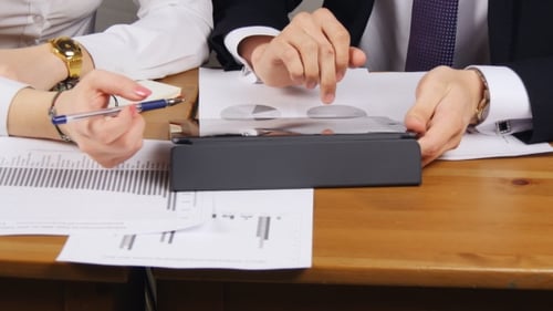 Business Meeting Analyzing Financial Data on Tablet