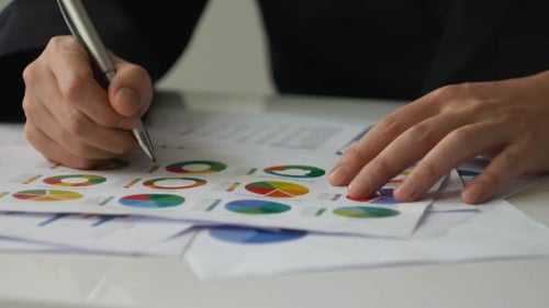 Hands Analyzing Financial Charts in Workplace