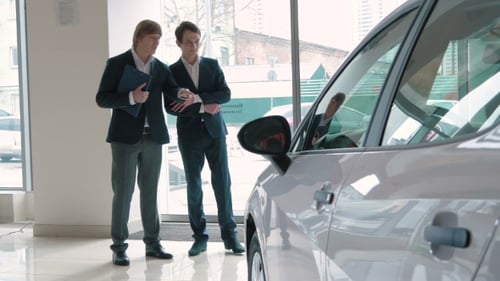 Two Men Discuss New Car Sales in Dealership