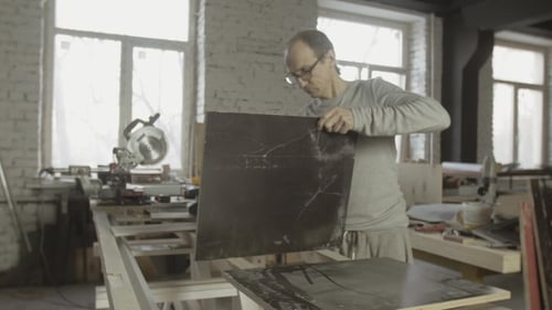 Man Inspecting Material in Bright Workshop