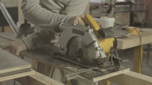 Man Cutting Wood with Power Saw in Workshop