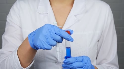 Medical Technician Extracting Blue Liquid from Test Tube