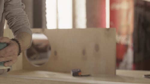 Man Sands Wood in Workshop with Power Sander