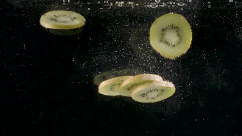 Kiwi Slices Falling into Water on Black Background