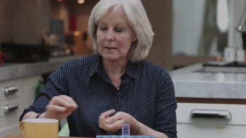 Mature Woman Taking Pills in a Kitchen
