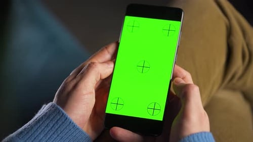 Man Using Smartphone with Green Mockup Screen in Vertical Mode