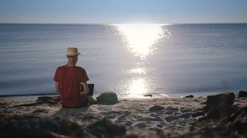 Young Adult Using Laptop on Sunny Beach