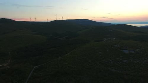 Sonnenuntergang hinter Hügeln mit Windmühlen im Hintergrund