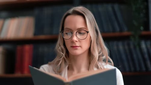 Closeup Blonde Woman in Vintage Eyeglasses Reading Interesting Paper Book Turning Page at Library