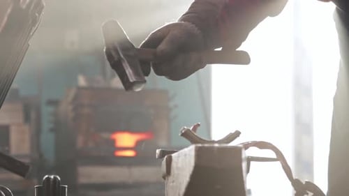 Blacksmith Shaping Hot Metal With Hammer on Anvil
