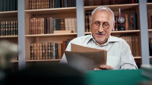 Close Up Grandfather Reading Paper Letters From Relatives and Friends Sitting at Table in Library
