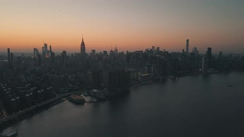 AERIAL: Over East River Showing Manhattan New York City Skyline in Beautiful Dawn Sunset Orange