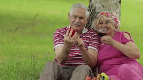 Family Picnic. Senior Old Grandparents Couple in Park Using Smartphone Online Browsing, Shopping
