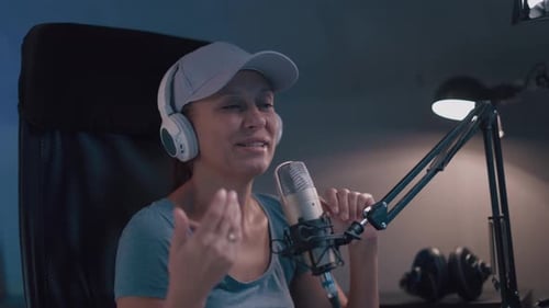 Beautiful Woman In A Cap And White Headphones Leads A Live Stream