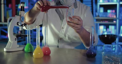 Scientist pours red liquid into a measuring cup