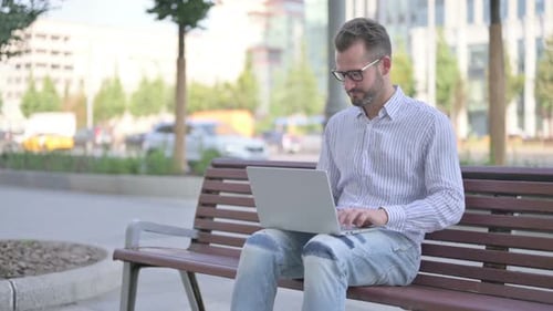 Man Working on Laptop in City Park