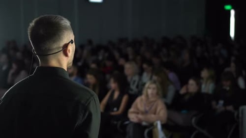 Business Conference Speaker Addressing Large Audience in Auditorium