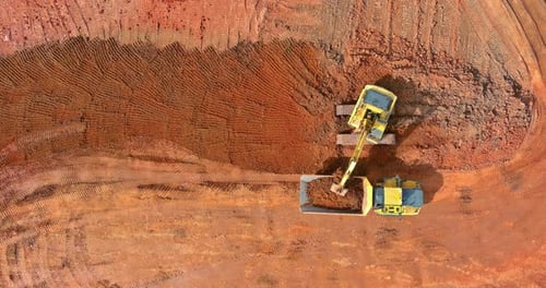 Aerial Top Down View of an Excavator Loading Earth Into a Dump Truck