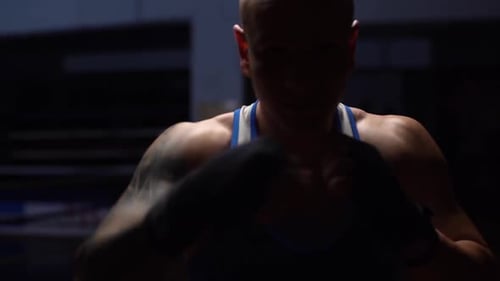 Front View of Unrecognizable Aggressive Boxer Male Wearing Bandages Punching Air to Camera in Sport