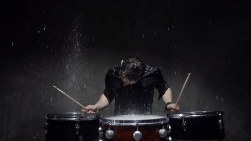 Drummer Energetically Playing Drums in the Rain