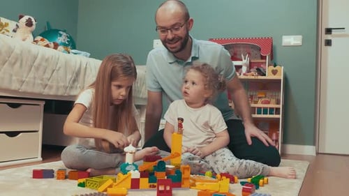 Father and Daughters Building with Toy Blocks