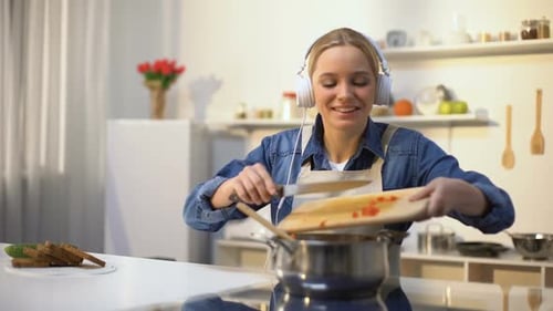 Woman Enjoys Cooking and Music in Bright Kitchen