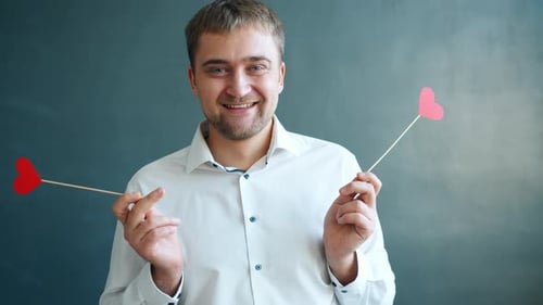 Happy Man Holding Red Heart Decorations