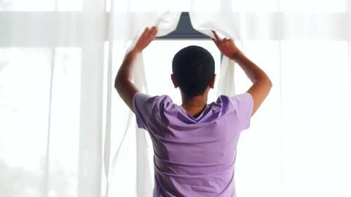 African American Woman Opens Window Blinds at Home