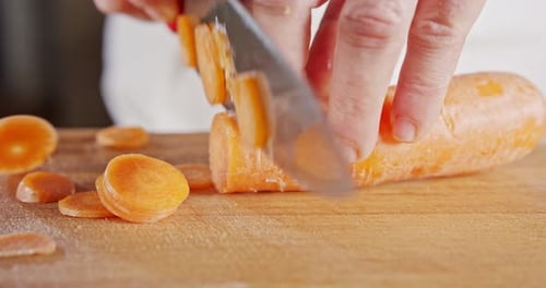 Close up of a chef knife slicing a carrot