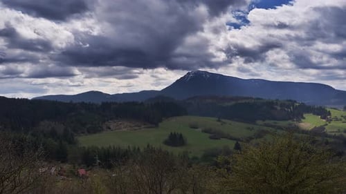 Mouvement de nuages denses sur le paysage printanier avec une montagne pointue