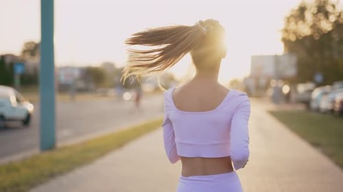 A Young Woman Runner is Training in the Summer Within a City