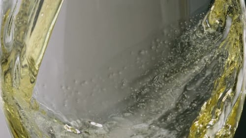 Yellow Liquid Pouring into Glass Container