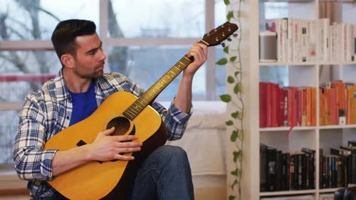 Young Adult Playing Acoustic Guitar Indoors