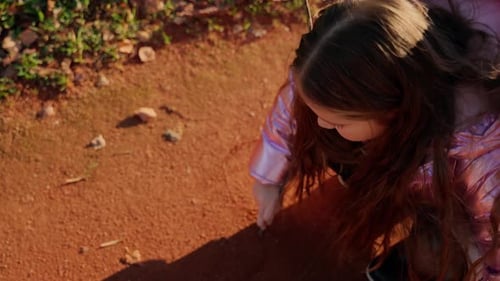 Girl play with branch and paint on ground close up outdoors. Female child having fun outside