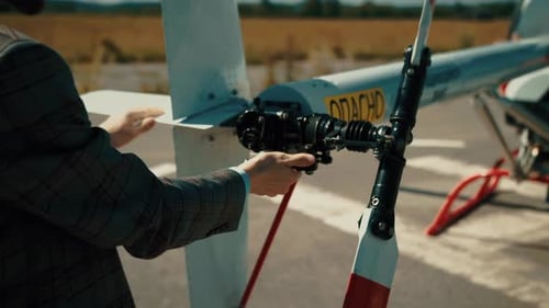 Man Adjusting Rotor on Unmanned Aircraft on Runway