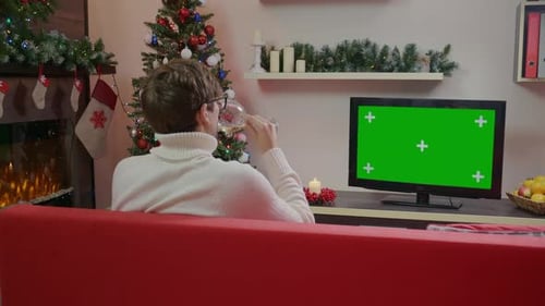 Christmas holidays concept. Man is watching Green Screen TV and drink
