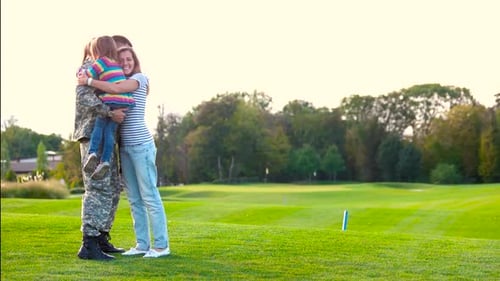 Family Embraces Soldier in Green Urban Setting