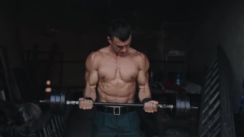 Close View of a Strong Sportsman Lifting a Barbell in the Gym
