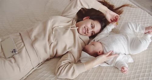Smiling Woman Bonding With Baby On Bed