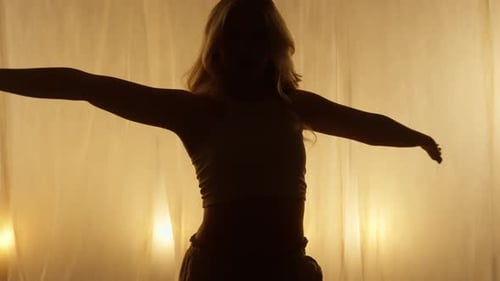 Silhouette einer professionellen Tänzerin, die im Studio bei sanftem, warmem Licht auftritt