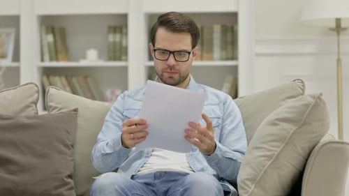 Man Reading Documents at Home on the Sofa
